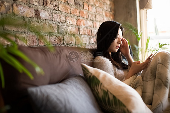 沙发上拿着手机的女青年图片