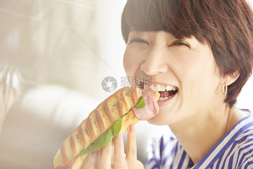 吃着三明治开心的青年女子图片