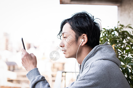 阳台上看手机听歌的男子图片