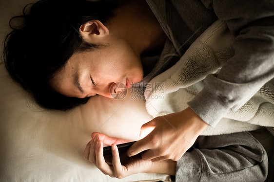 夜晚男人躺看着智能手机生活方式图片