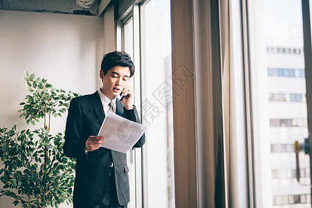 雇员一人工作新招的男在窗边打电话图片
