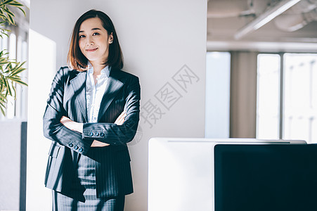 雇员女单人倾斜在柱子的微笑的妇女在办公室图片