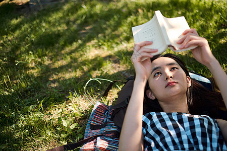 躺在草坪上阅读的女青年图片