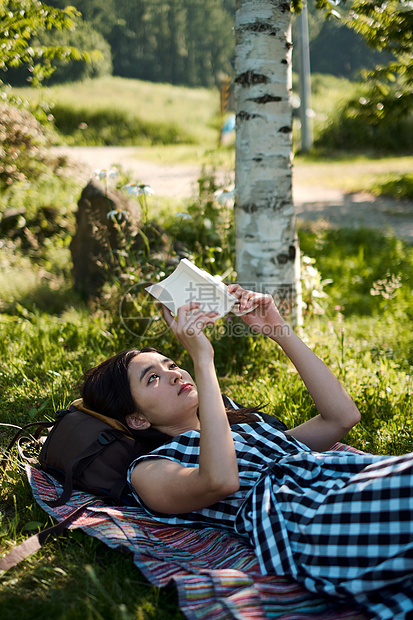 户外草坪阅读的女青年图片
