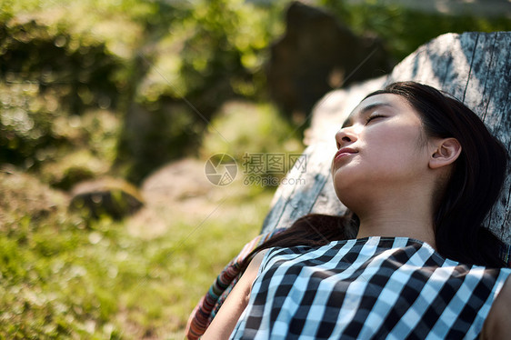 躺在木头上闭眼休息的女青年图片