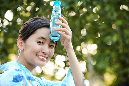 拿着水杯额头降温的年轻女子图片