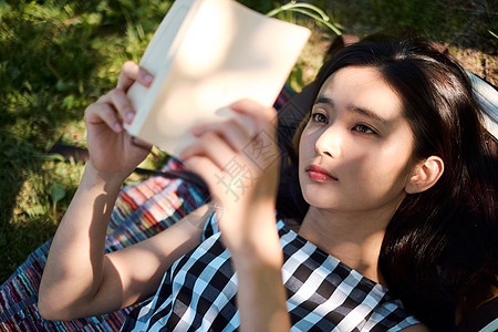躺在草坪上阅读的年轻女子图片