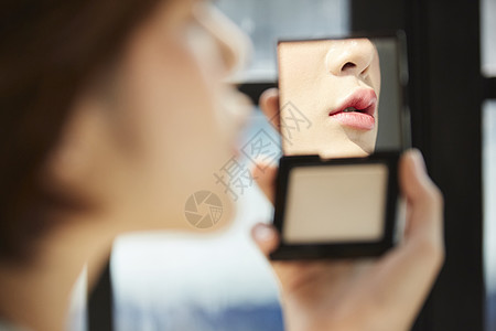 手拿化妆镜的美女背景图片