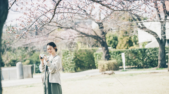 拍摄爱好享受樱花拍照片的春天妇女图片