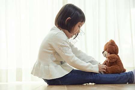 三岁全年的学前班儿童女孩坐在地板上和玩一只小熊图片