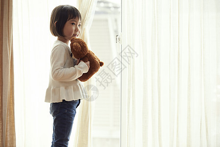 室内抱玩具熊的女孩图片