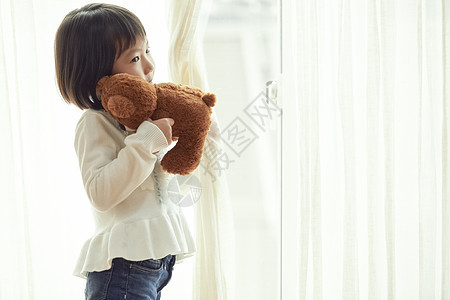 室内抱玩具熊的女孩图片