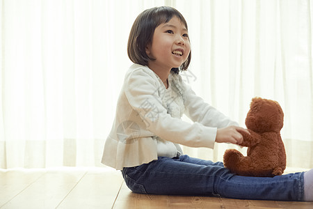 室内抱玩具熊的女孩图片