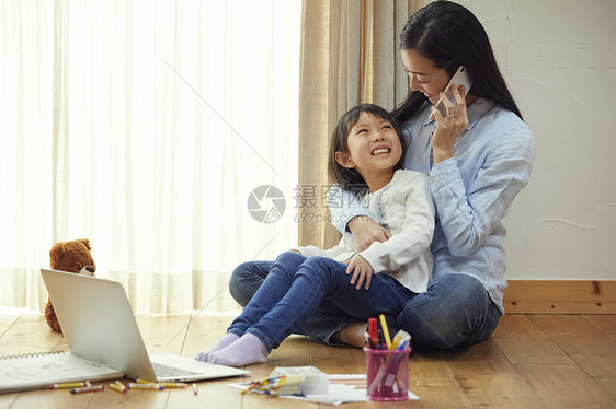 妈妈抱着女儿在地板上打电话图片