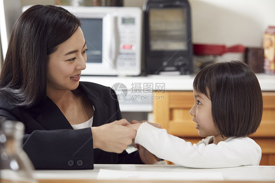 在厨房里母亲照顾抓着女儿的手图片