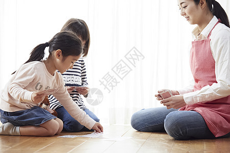 老师和孩子坐在地板上玩纸牌图片