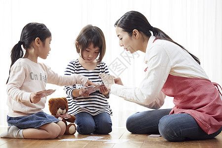 老师和孩子坐在地板上和玩纸牌图片