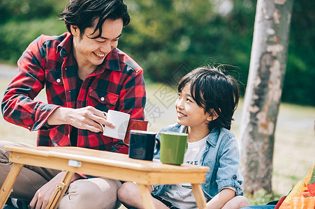 坐在地上喝饮料的父子图片