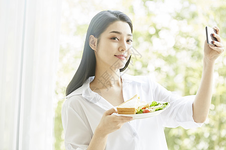 拿手机拍食物的居家女孩图片