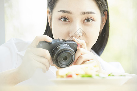 拿相机拍食物的居家女孩图片