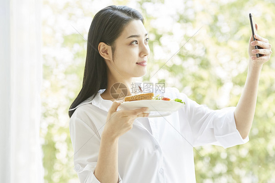 拿手机拍食物的居家女孩图片