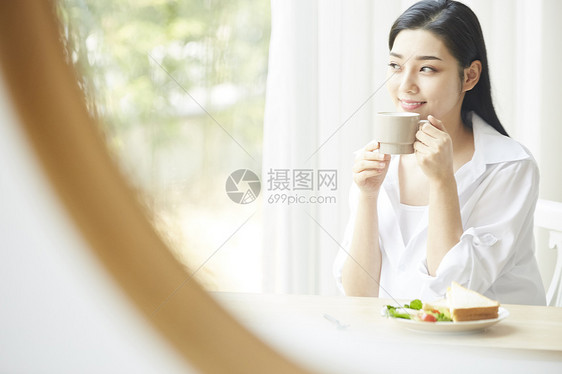 享用早餐喝咖啡的女青年图片