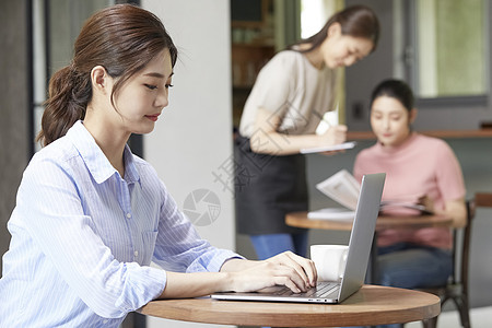 咖啡馆使用笔记本电脑的年轻女子图片