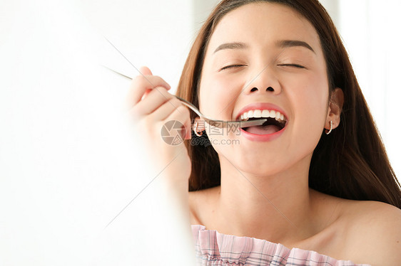 拿着勺子吃食物的年轻女子图片
