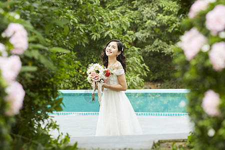 泳池边拿着手捧花的美丽新娘图片