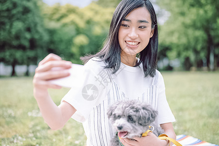 公园里抱着宠物狗自拍的女人图片