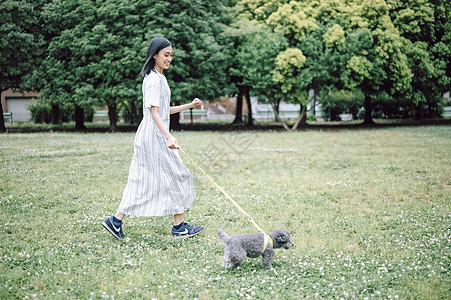 草坪上遛狗的年轻女子图片