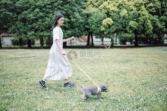 草坪上遛狗的年轻女子图片