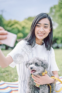 抱着宠物狗自拍的年轻女子图片