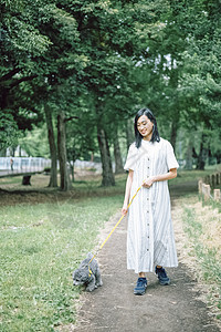 公园里遛狗的年轻女子图片