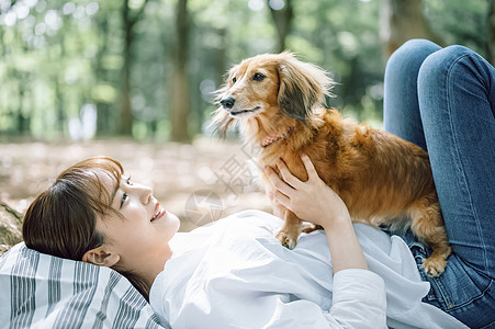 公园郊游抱着狗狗的女主人图片