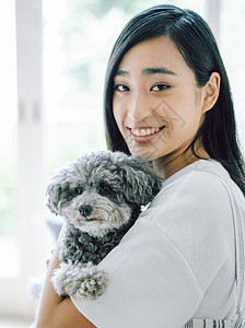 室内微笑的女人抱着宠物狗图片