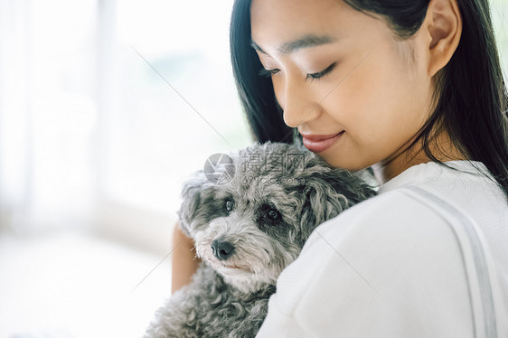 室内微笑的女人抱着宠物狗图片