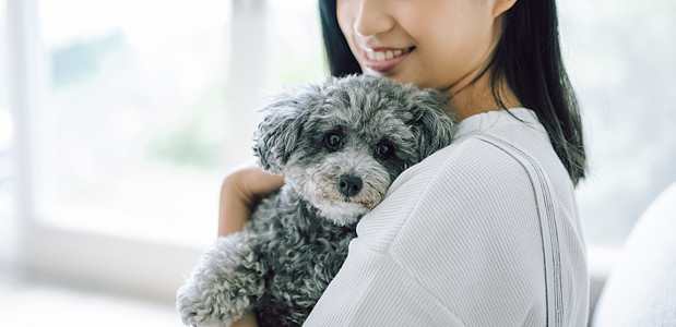 室内微笑的女人抱着宠物狗图片