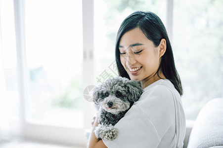 室内微笑的女人抱着宠物狗图片