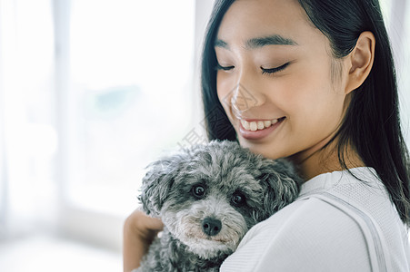 窗边抱着宠物狗的女人图片