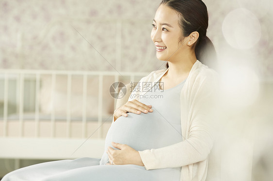 抚摸肚子微笑的年轻孕妇图片