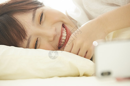 可爱女生开心的在床上看手机图片