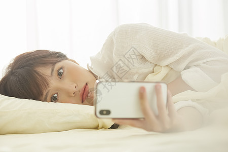 可爱女生在床上看手机图片