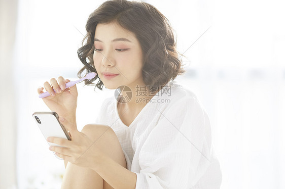 拿着牙刷看手机的女青年图片