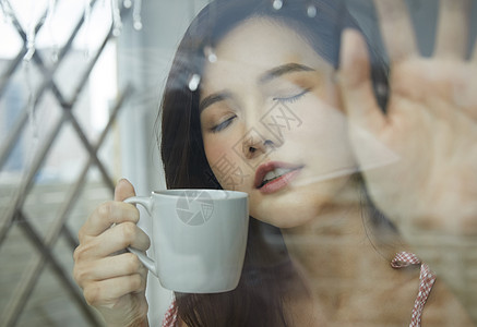下雨天喝咖啡的年轻女子图片