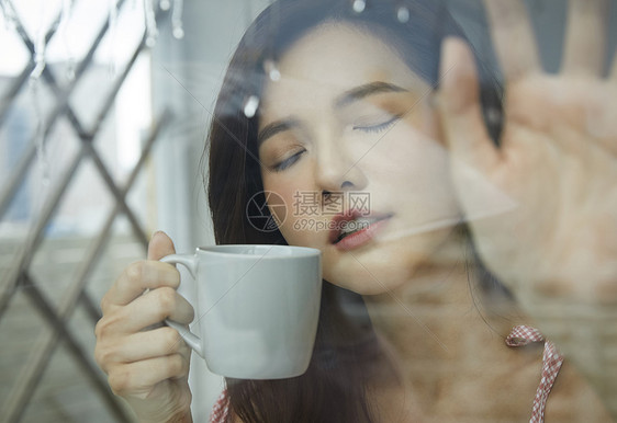 下雨天喝咖啡的年轻女子图片