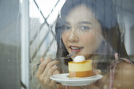 下雨天吃着甜品的女青年图片