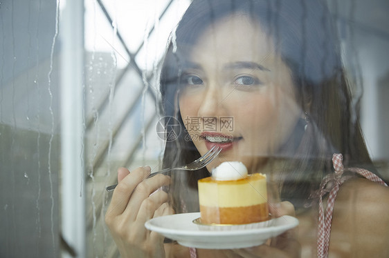 下雨天吃着甜品的女青年图片