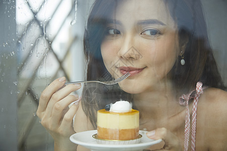 下雨天咖啡馆吃甜品的年轻女子图片