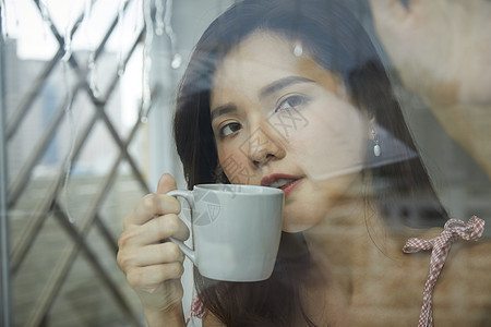 窗边看手机的年轻女人图片